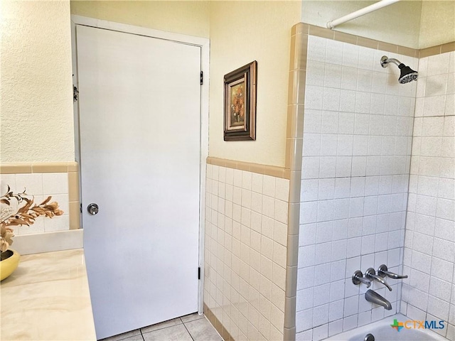 bathroom with tile patterned floors, tiled shower / bath, and tile walls