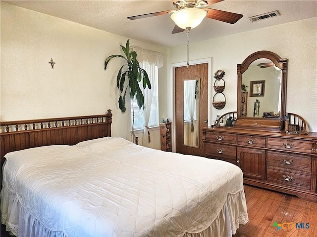 bedroom featuring a textured ceiling, ceiling fan, and dark wood-type flooring