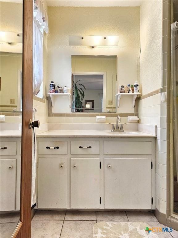 bathroom with tile patterned flooring, vanity, and a shower