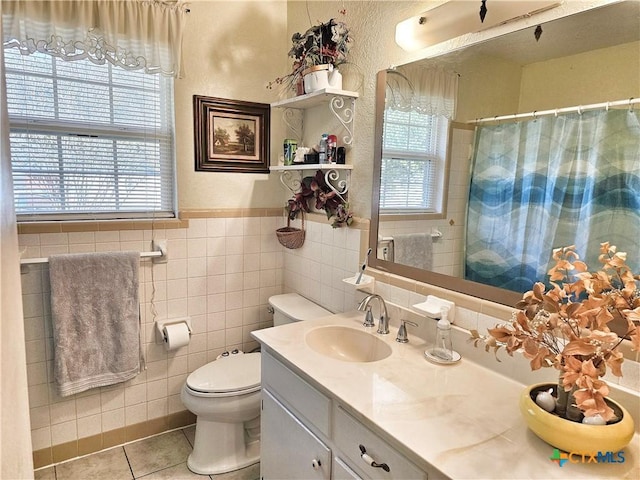 bathroom featuring tile patterned floors, vanity, tile walls, and toilet