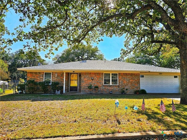 ranch-style house featuring a front lawn, an attached garage, fence, and brick siding