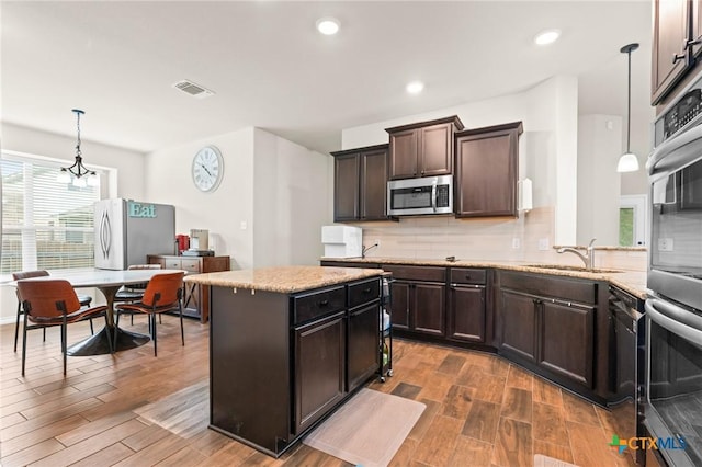 kitchen featuring appliances with stainless steel finishes, a sink, visible vents, and wood finished floors