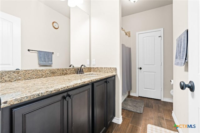 full bathroom featuring vanity, a shower, wood finished floors, toilet, and baseboards