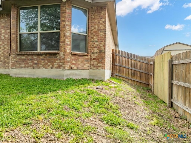 view of property exterior with a lawn, brick siding, and fence