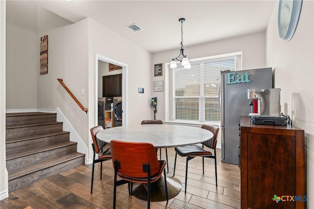 dining room with visible vents, stairs, wood finished floors, baseboards, and washing machine and clothes dryer