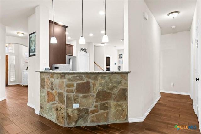 kitchen with arched walkways, baseboards, freestanding refrigerator, and wood finished floors