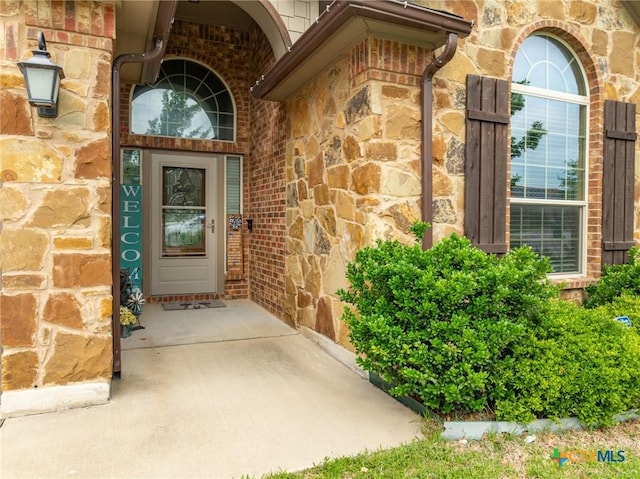 view of exterior entry with brick siding and stone siding