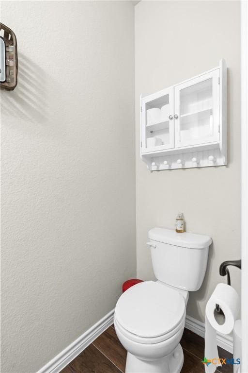 bathroom with baseboards, toilet, and wood finished floors