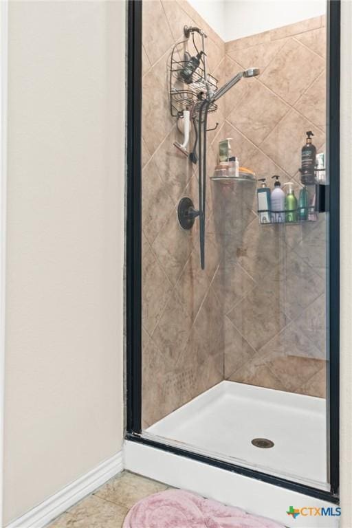 bathroom with tile patterned flooring, baseboards, and a shower stall