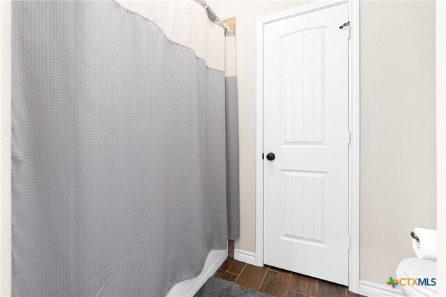 full bathroom featuring toilet, baseboards, curtained shower, and wood finished floors