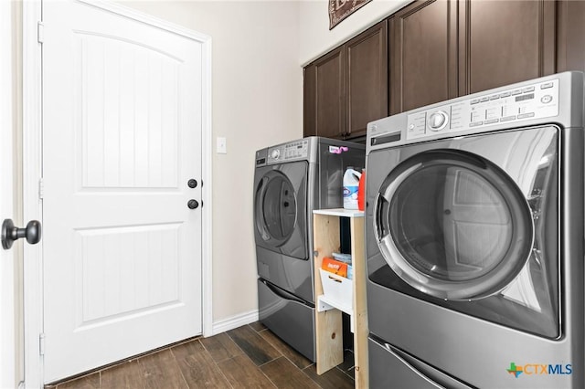 clothes washing area with separate washer and dryer, baseboards, dark wood-style floors, and cabinet space