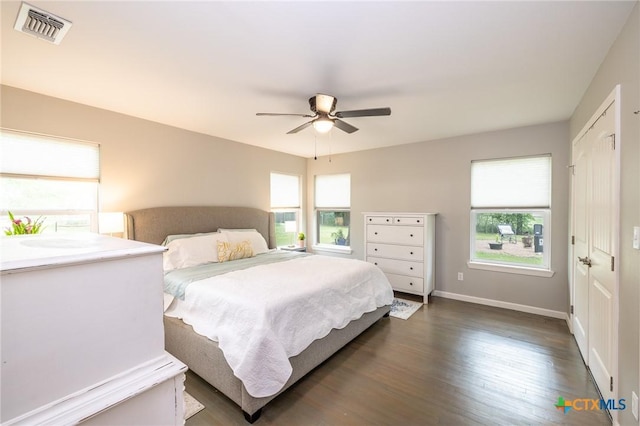bedroom featuring multiple windows, dark wood finished floors, ceiling fan, and visible vents