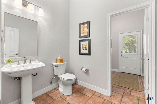 half bathroom with a sink, toilet, and baseboards