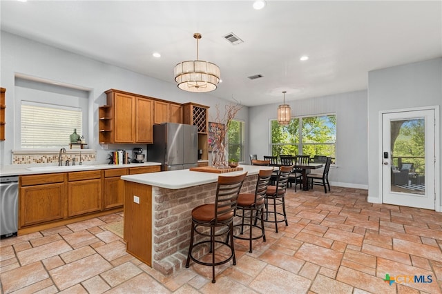 kitchen featuring open shelves, a sink, freestanding refrigerator, a center island, and brown cabinetry