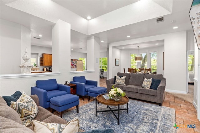 living area with recessed lighting, visible vents, stone tile floors, and baseboards