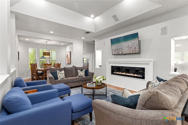 living room with a glass covered fireplace, visible vents, and recessed lighting