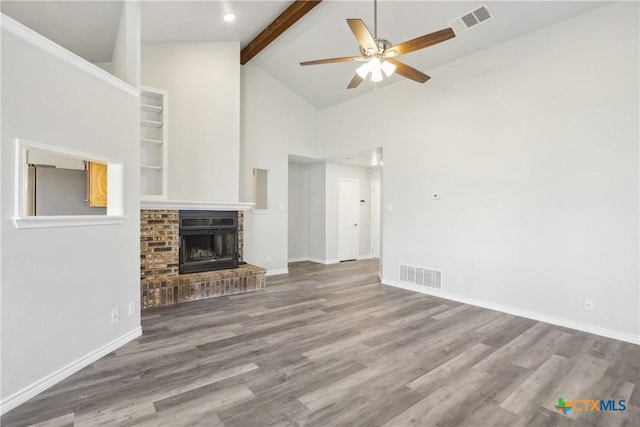 unfurnished living room featuring high vaulted ceiling, hardwood / wood-style flooring, ceiling fan, a fireplace, and beam ceiling