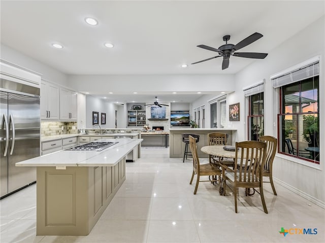 kitchen with white cabinetry, kitchen peninsula, appliances with stainless steel finishes, a center island, and decorative backsplash