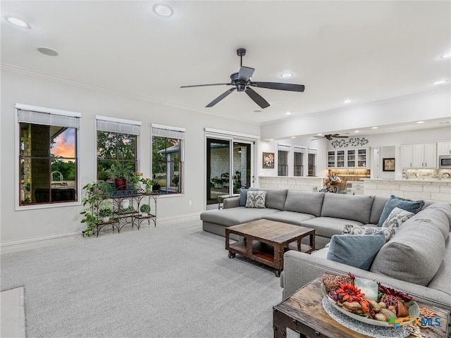 living room featuring ornamental molding, light colored carpet, and ceiling fan