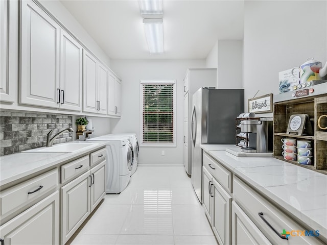 washroom featuring cabinets, light tile patterned flooring, sink, and independent washer and dryer