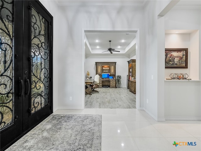 foyer with ornamental molding, ceiling fan, light tile patterned floors, a tray ceiling, and french doors