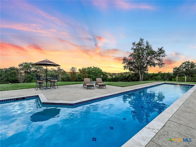 pool at dusk with a patio area