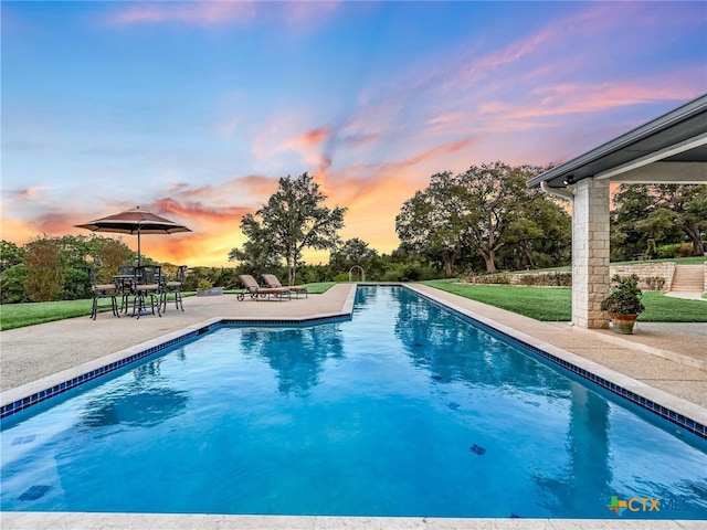 pool at dusk with a yard and a patio area