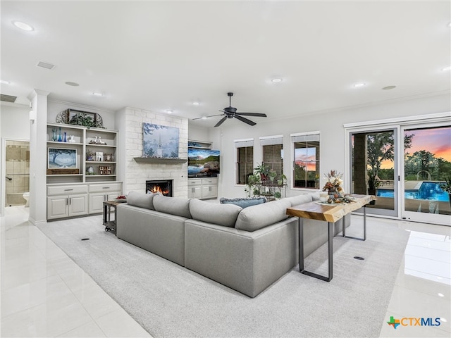 tiled living room featuring ornamental molding, a fireplace, and ceiling fan