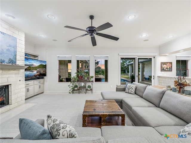 carpeted living room with a fireplace, ceiling fan, and crown molding