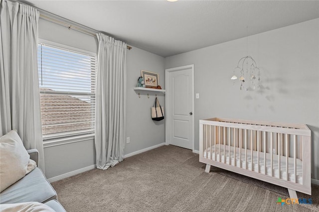 carpeted bedroom with a nursery area, baseboards, and a chandelier