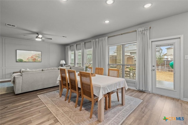 dining area featuring visible vents, recessed lighting, a decorative wall, and light wood-style floors