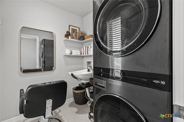 laundry room featuring laundry area, baseboards, tile patterned floors, and stacked washing maching and dryer