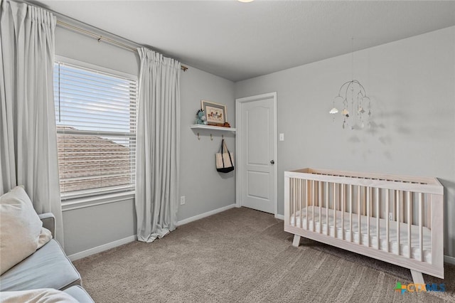 carpeted bedroom featuring baseboards, a chandelier, and a crib