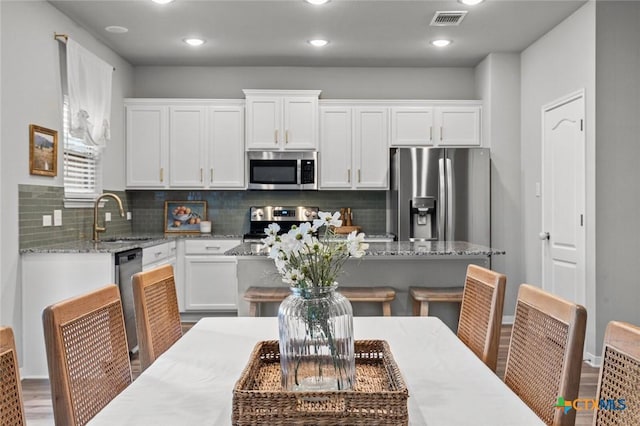 kitchen with a sink, visible vents, appliances with stainless steel finishes, and white cabinets