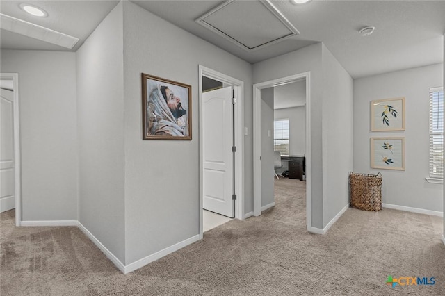 corridor featuring baseboards and carpet