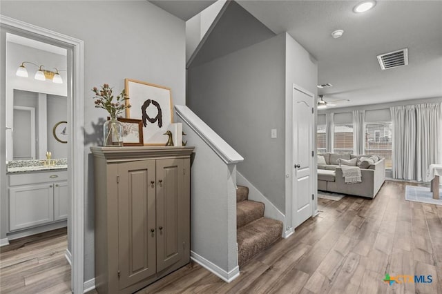 interior space featuring visible vents, a ceiling fan, baseboards, and wood finished floors