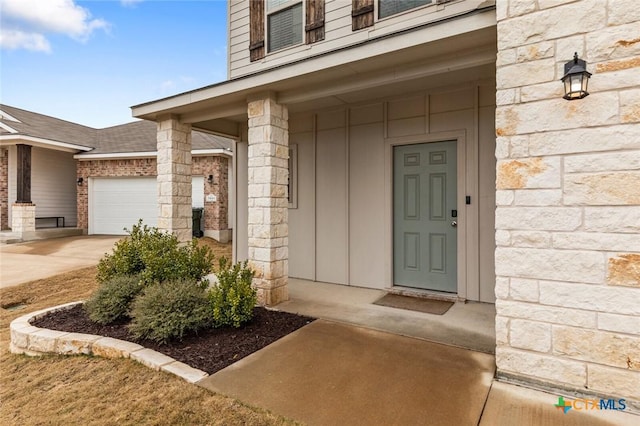 entrance to property with a garage and stone siding