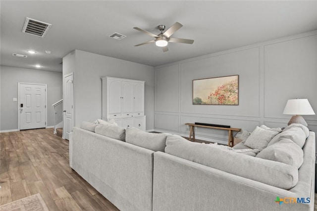 living area featuring a decorative wall, wood finished floors, and visible vents