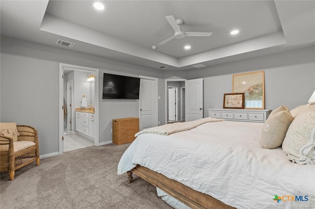 bedroom with light carpet, visible vents, and a raised ceiling