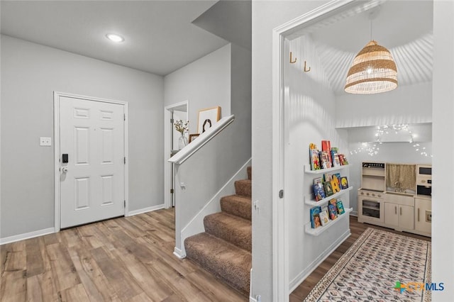 entrance foyer with stairs, baseboards, and wood finished floors