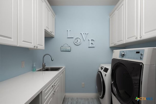 clothes washing area featuring sink, cabinets, and washing machine and dryer