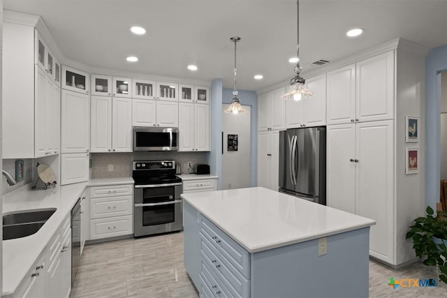 kitchen featuring white cabinetry, a center island, tasteful backsplash, hanging light fixtures, and appliances with stainless steel finishes