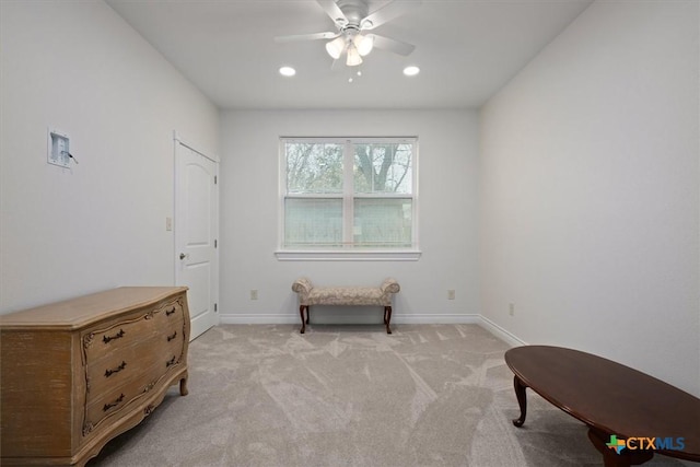 living area featuring light carpet and ceiling fan