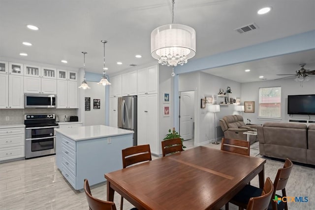 dining space with ceiling fan with notable chandelier