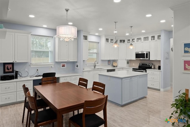 kitchen featuring sink, range with electric cooktop, decorative light fixtures, white cabinetry, and a center island