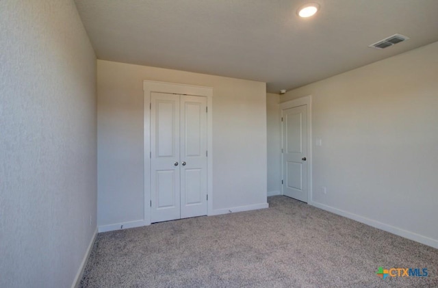 unfurnished bedroom featuring light carpet and a closet