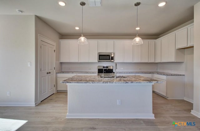 kitchen with stainless steel appliances, white cabinetry, a center island with sink, and sink