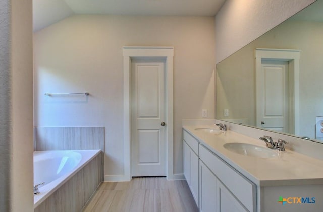 bathroom with lofted ceiling, vanity, and a bathing tub