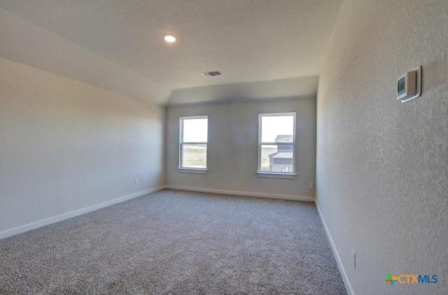 carpeted spare room featuring vaulted ceiling