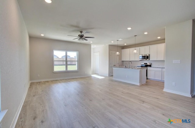 kitchen with white cabinetry, light hardwood / wood-style floors, decorative light fixtures, and appliances with stainless steel finishes